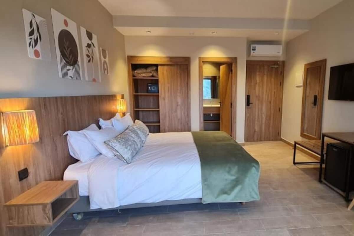 A modern bedroom with a bed, bedside tables, a desk, and a TV.