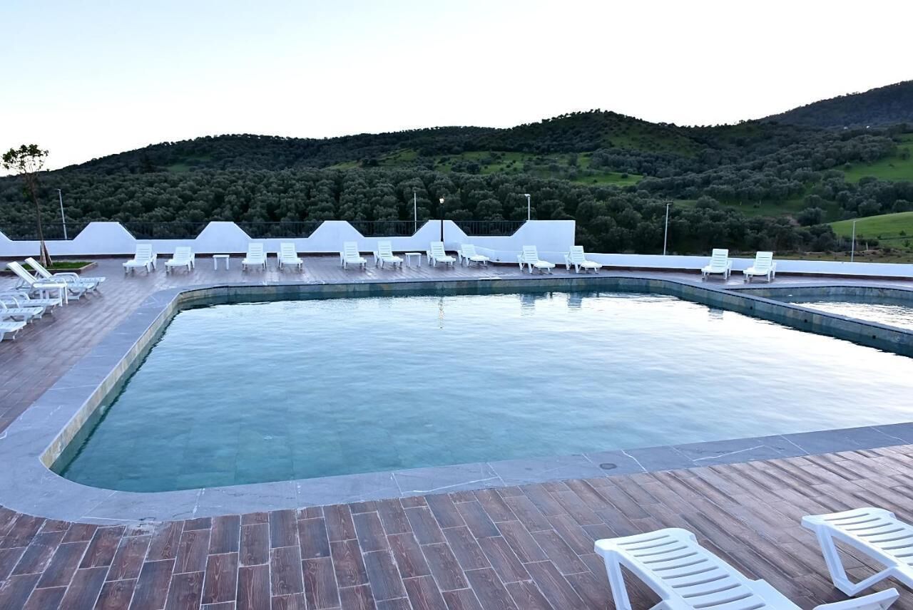 A rectangular pool with white lounge chairs and a wooden deck.