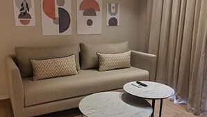 Una sala de estar moderna con un sofá color beige, dos mesas redondas de centro y un cuadro abstracto en la pared.