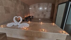 Un área de recepción de mármol con una disposición de toallas con forma de cisne y velas.