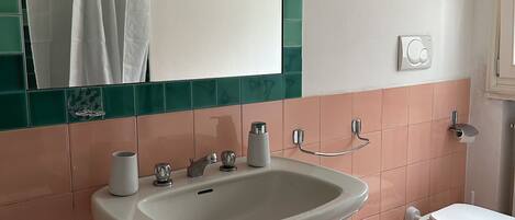 A bathroom with a sink, mirror, toilet, bidet, and a towel rack.