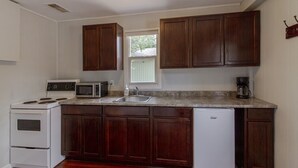 A compact kitchen with a stove, microwave, sink, and refrigerator. - Westlake Couple`s Cottage (Prince Edward)