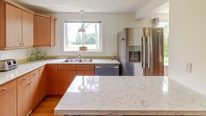 Una cocina moderna con armarios de madera, un refrigerador de acero inoxidable, lavavajillas integrado y encimera de mármol.