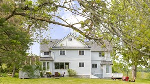 A two-story house with a front porch, a small deck, and a large tree in the foreground. - Family friendly duplex (Prince Edward)