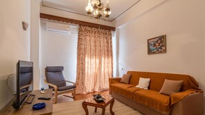Una sala de estar con sofá, sillón, televisor y una mesa de centro.