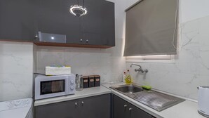 Una cocina compacta con microondas, lavamanos y armarios.