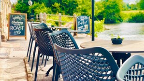 Outdoor seating with metal chairs and tables, a sign for Sunday Roast, and another for Cider and Coffee. - Old Mill Salisbury (Salisbury)