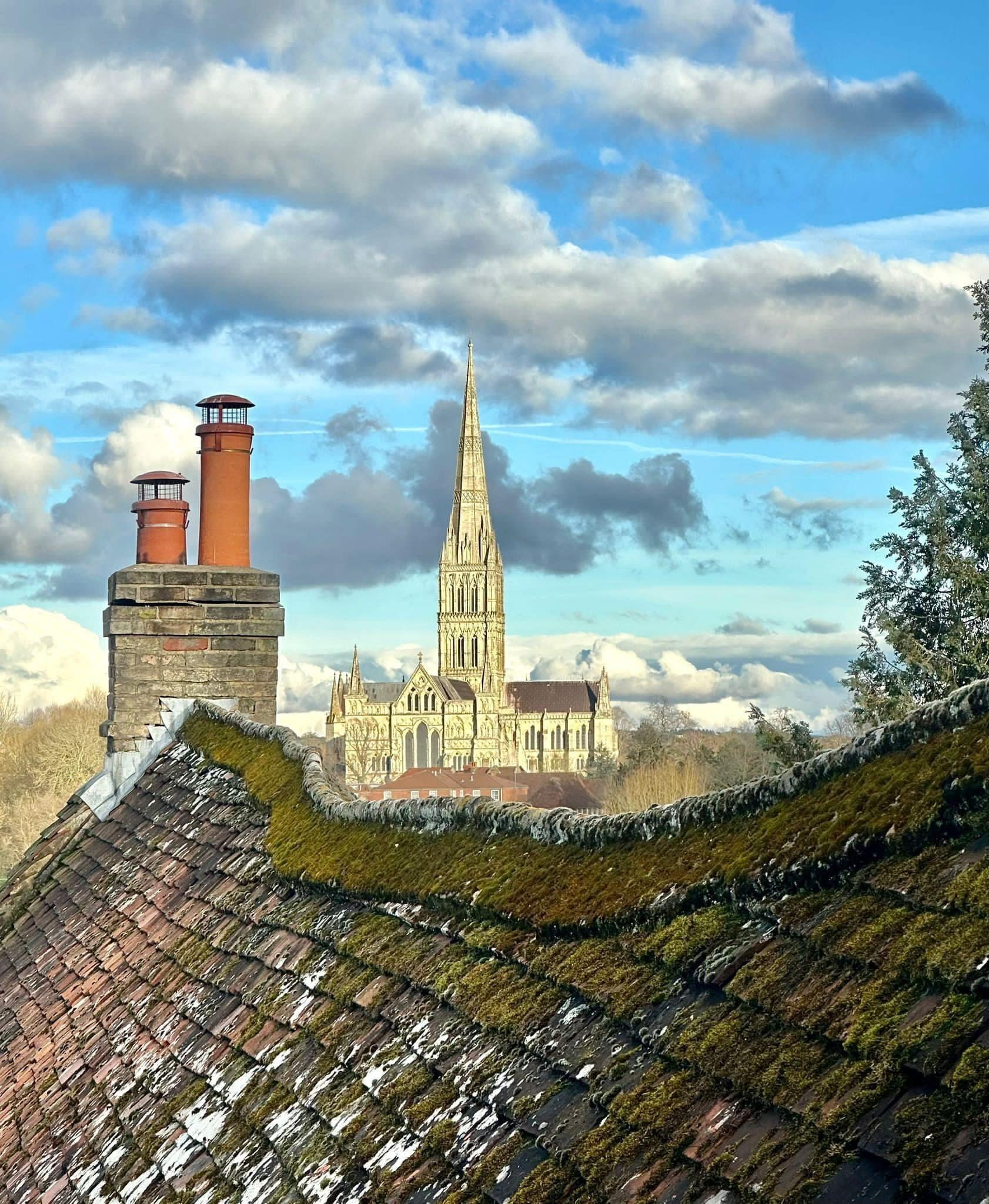 Un bâtiment historique doté d’une haute flèche et d’une cheminée en briques.
