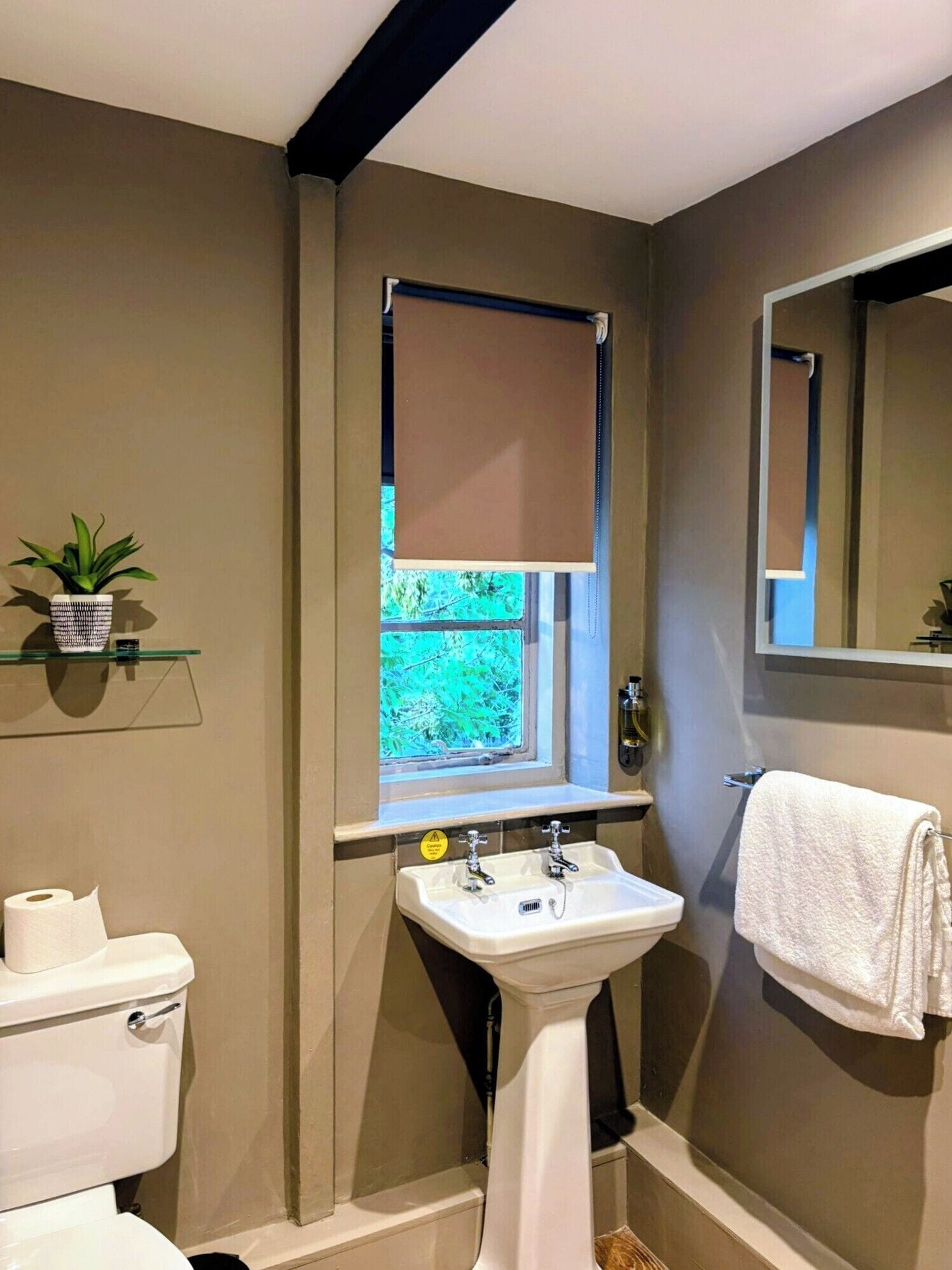 Ein Badezimmer mit Toilette, Waschbecken und einem Fenster mit Jalousien.