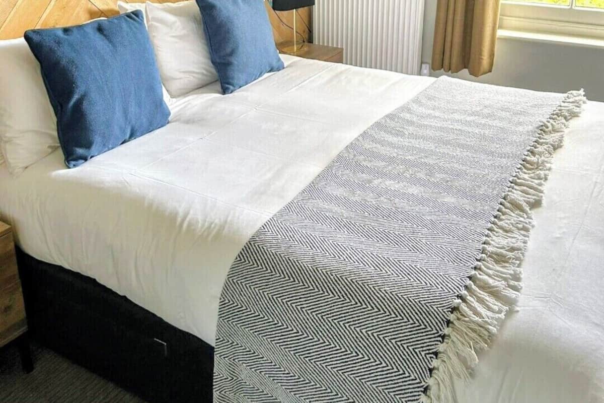 A neatly made bed with a floral headboard, two pillows, and a patterned throw blanket.