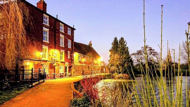 A traditional brick building with a well-lit entrance and a pathway leading to a body of water. - Old Mill Salisbury (Salisbury)