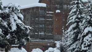 Un bâtiment enneigé, doté de plusieurs étages et de balcons, entouré d’arbres chargés de neige.