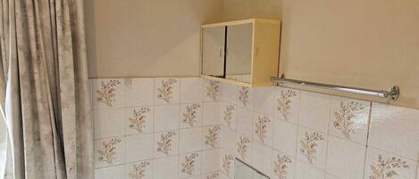 A bathroom with a bathtub, a mirror, and a towel rack.