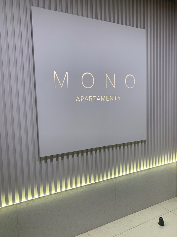 A sign for "MONO APARTMENT" with a modern design and illuminated strip lights.