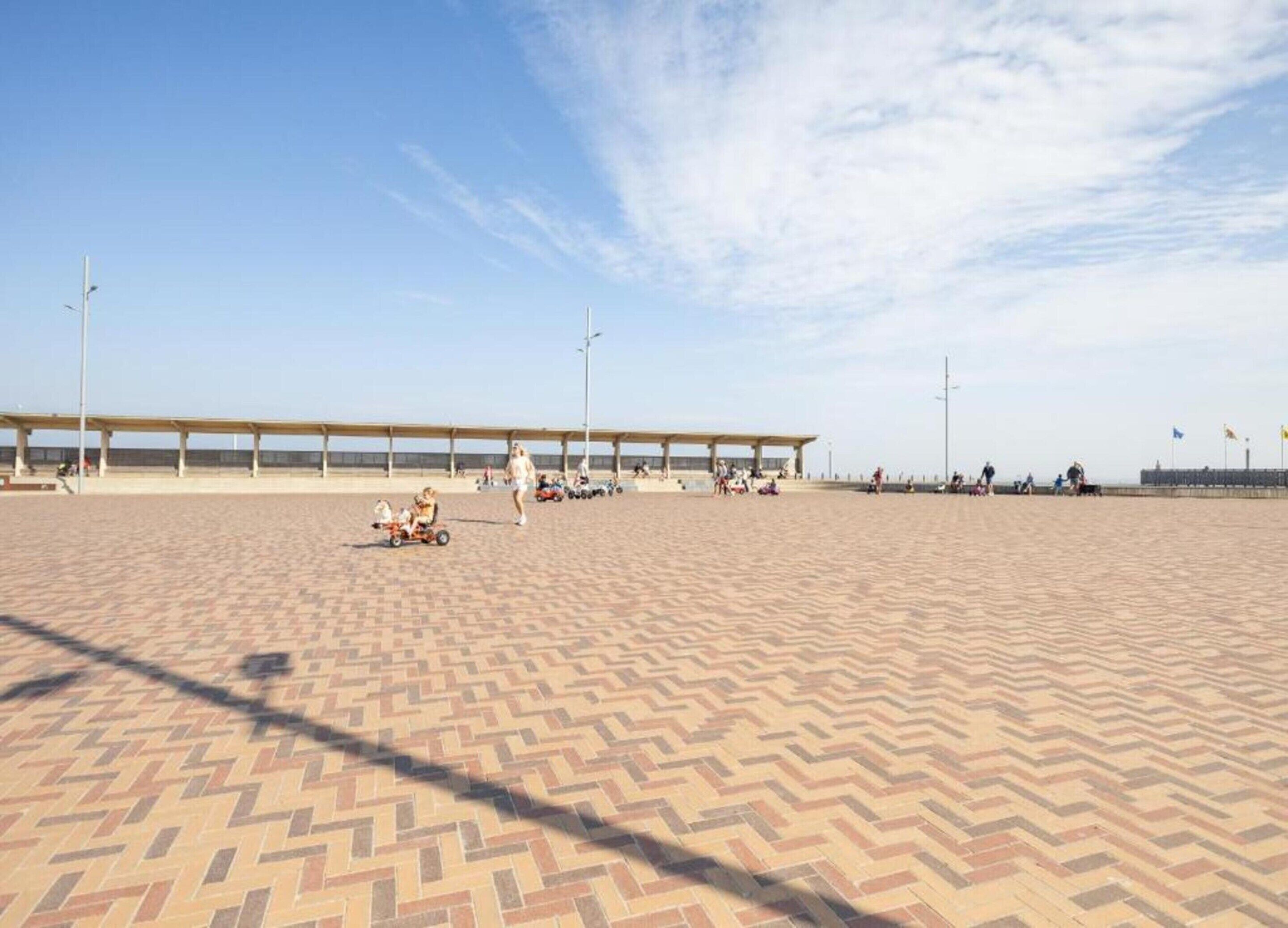 Een strand met een verharde promenade, een overdekte zitplaats en een heldere lucht.