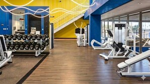 Ein Fitnessraum mit Trainingsgeräten, einer Hantelbank und einer Treppe.