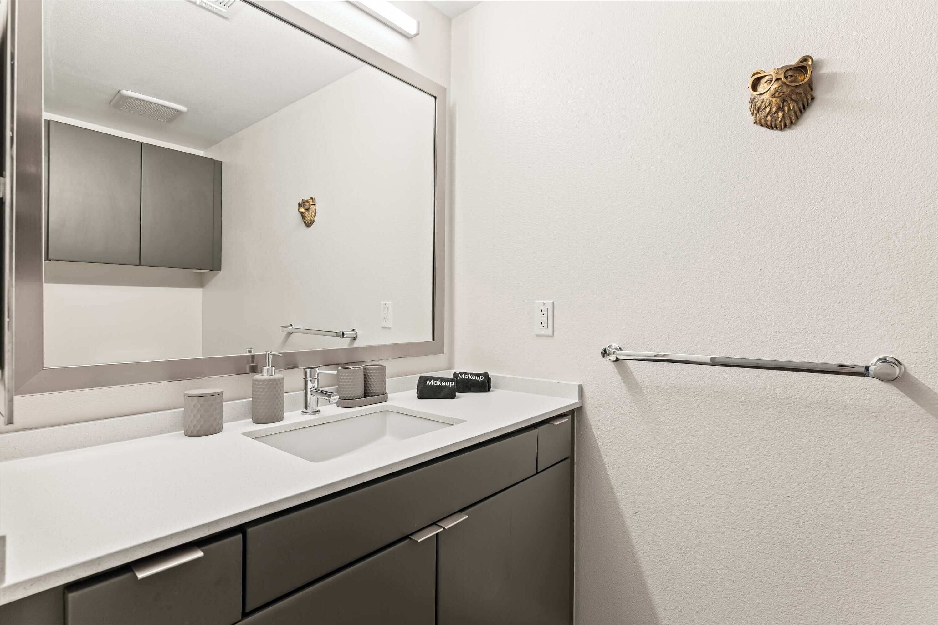 Une salle de bain moderne avec un grand miroir, deux lavabos, un porte-serviettes et un élément décoratif mural.