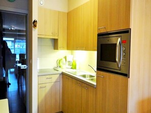A modern kitchen with wooden cabinets, a stainless steel refrigerator, and a microwave. - Apartment in Wenduine Near the Beach (De Haan)