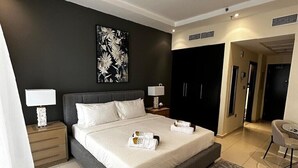 A modern hotel room with a large bed, a dark accent wall, and a view of the hallway. - Skyview Tower (Dubai)