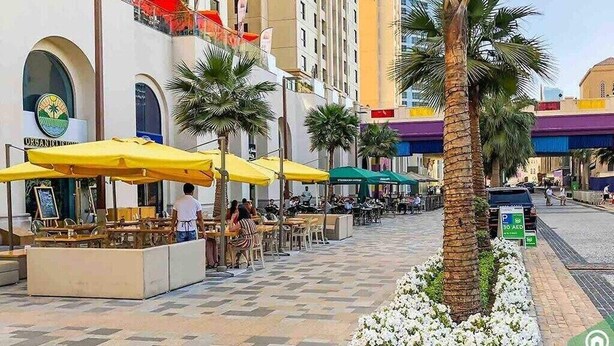 A street with outdoor seating, palm trees, and a building with a sign that reads "ORGANIC." - Skyview Tower (Dubai)