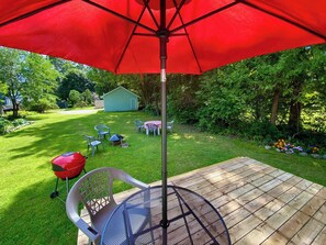 A patio with a metal table and chairs, a red umbrella, and a wooden deck. - Downtown Sturgeon Bay Treasure (Sturgeon Bay)