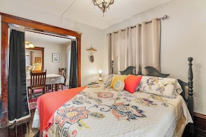 Un dormitorio con cama, una silla, una mesa y una araña.