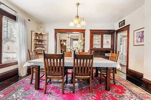 A dining room with a table, chairs, a chandelier, and a patterned rug. - Downtown Sturgeon Bay Treasure (Sturgeon Bay)