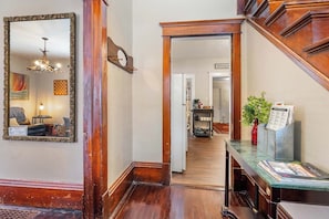 A hallway with a mirror, a wooden door, a small table with a vase, and a sign for 'Antenzo's'.