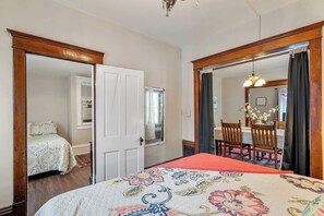 A bedroom with a bed, a wardrobe, a mirror, and a dining area with chairs and a table. - Downtown Sturgeon Bay Treasure (Sturgeon Bay)