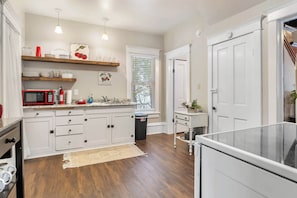 A kitchen with white cabinets, a red microwave, and a wooden countertop.
