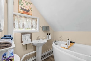 Ein Badezimmer mit einer Badewanne, einem Waschbecken, einem Fenster mit Vorhängen und einem Handtuchhalter.