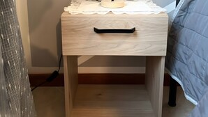 Une table de chevet en bois, avec une lampe, un tiroir et une étagère.