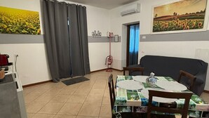 Un coin repas avec une table dressée pour quatre personnes, un canapé gris et un tableau représentant un champ accroché au mur.