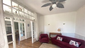 Un salon spacieux doté d’un plancher en bois, d’un canapé rouge, d’une table basse ronde et d’un ventilateur de plafond.