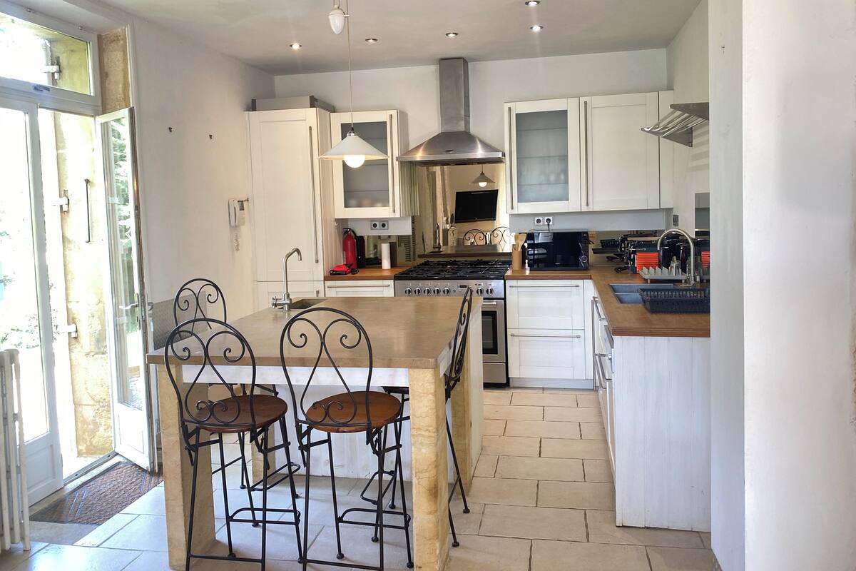 A modern kitchen with white cabinets, a central island with bar stools, a stove, and a microwave.