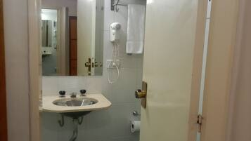 Et badeværelse med vask, spejl, håndklædestige og toilet.