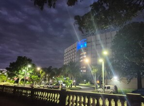 A multi-story building with illuminated windows at night, surrounded by trees and streetlights.