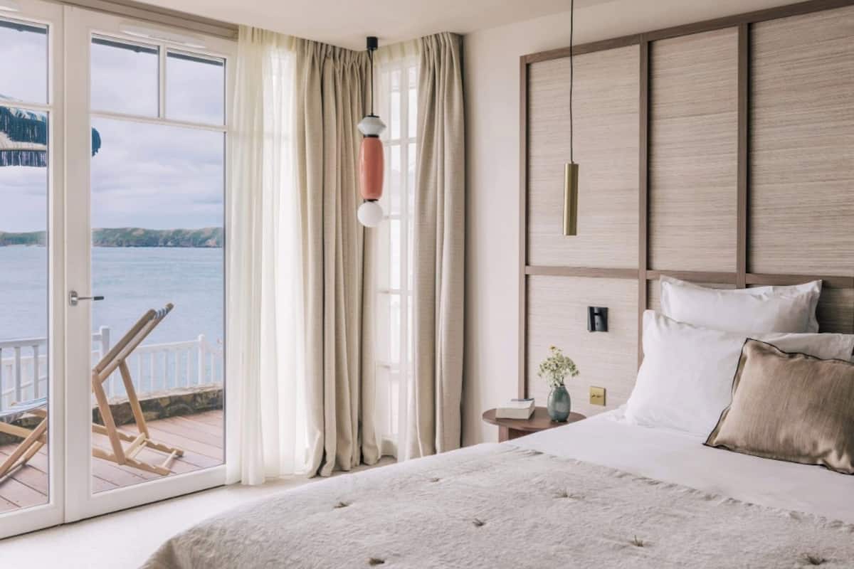 A bedroom with a large bed, a view of the sea, and a wooden headboard.