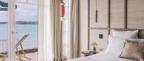 A bedroom with a large bed, a view of the sea, and a wooden headboard.