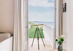 A balcony with a tripod, a vase with flowers, and a view of the sea. - Les Bassans - Fontenille Collection (Perros-Guirec)