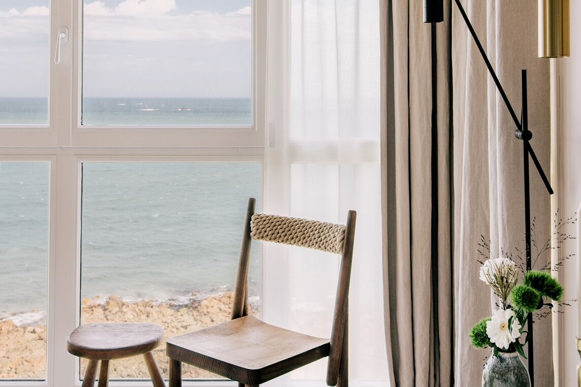 Una silla junto a una ventana con vista al mar.