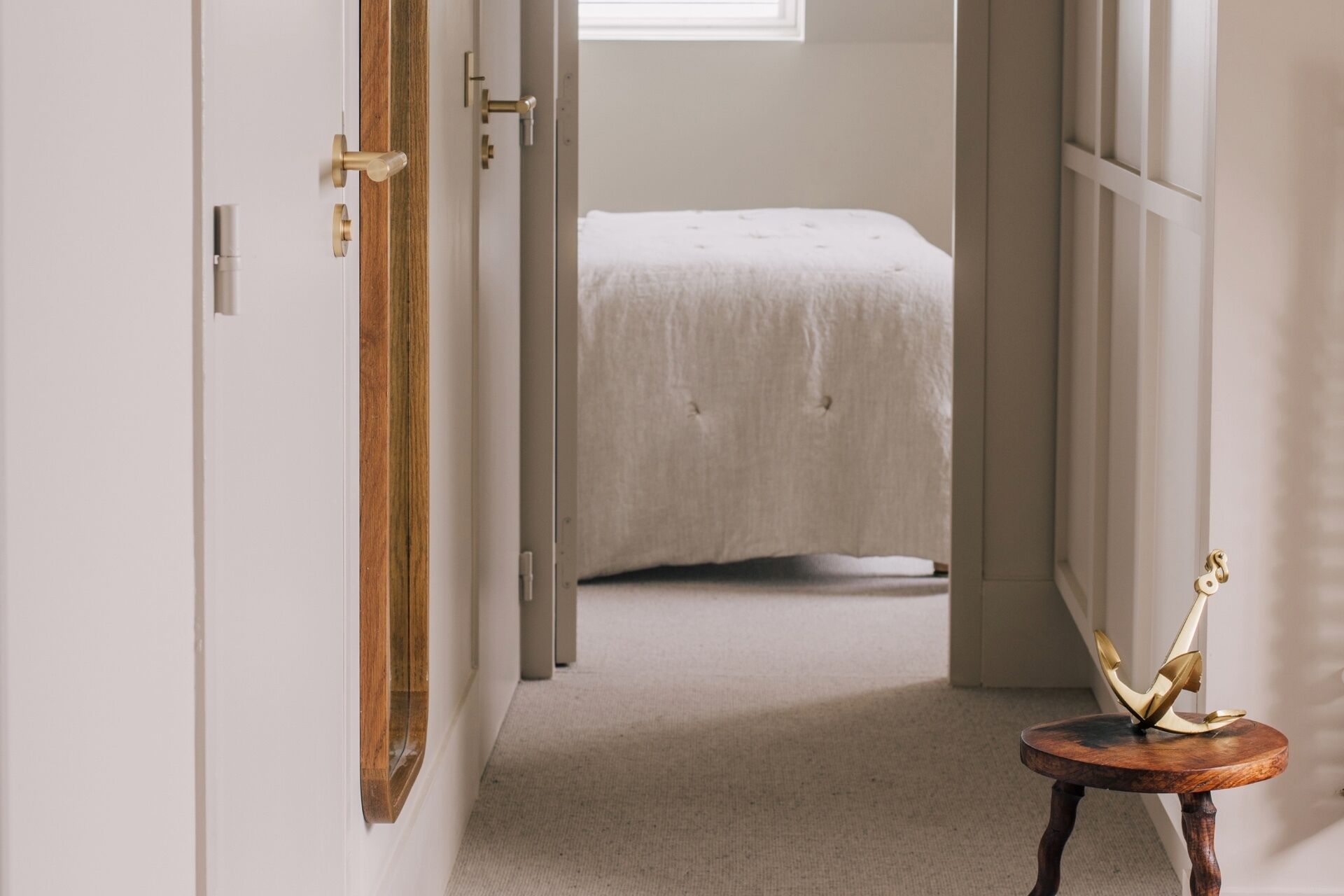 Une chambre à coucher avec un lit, une porte en bois et une petite table sur laquelle se trouve un objet décoratif.