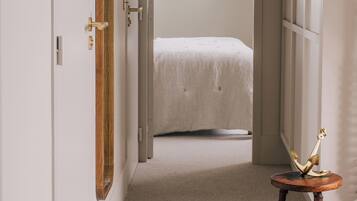 Une chambre à coucher avec un lit, une porte en bois et une petite table sur laquelle se trouve un objet décoratif.
