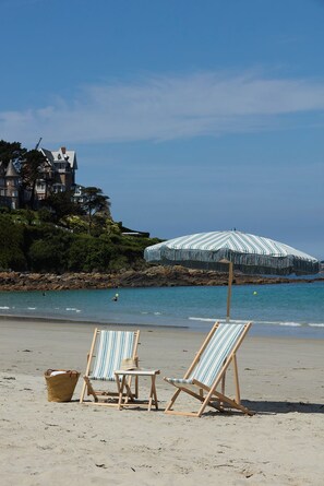 A beach with two striped beach chairs, a wicker basket, and a striped umbrella. - Les Bassans - Fontenille Collection (Perros-Guirec)