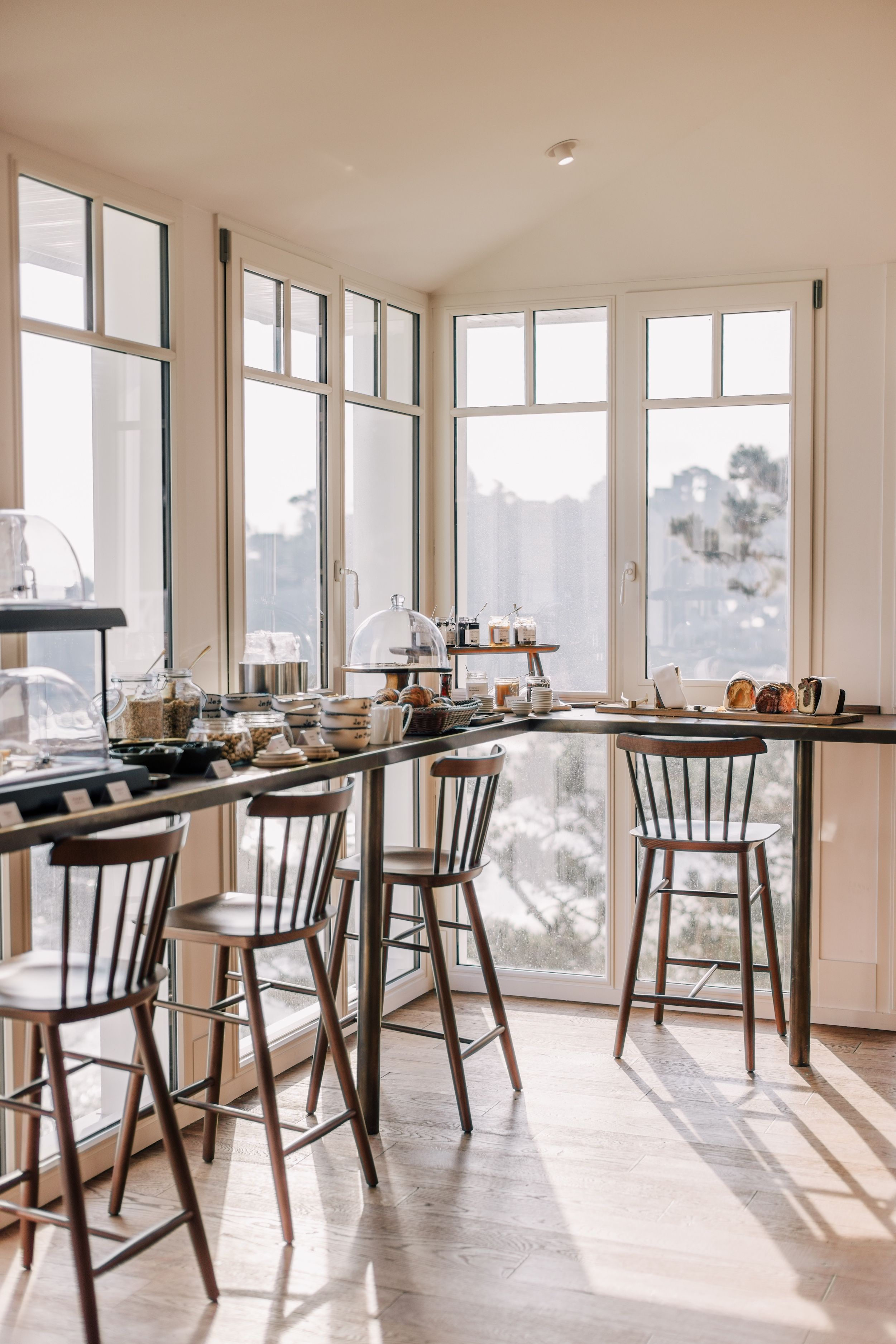 Une cuisine dotée d’une grande fenêtre, d’une table à manger avec des chaises et de divers ustensiles de cuisine.