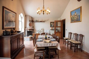 A dining area with a table set for four, surrounded by wooden chairs, a chandelier, and artwork on the walls.