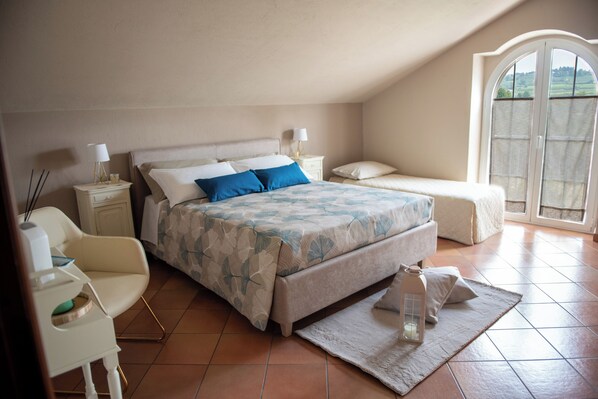 A bedroom with a bed, bedside tables, a chair, and a window with a view.
