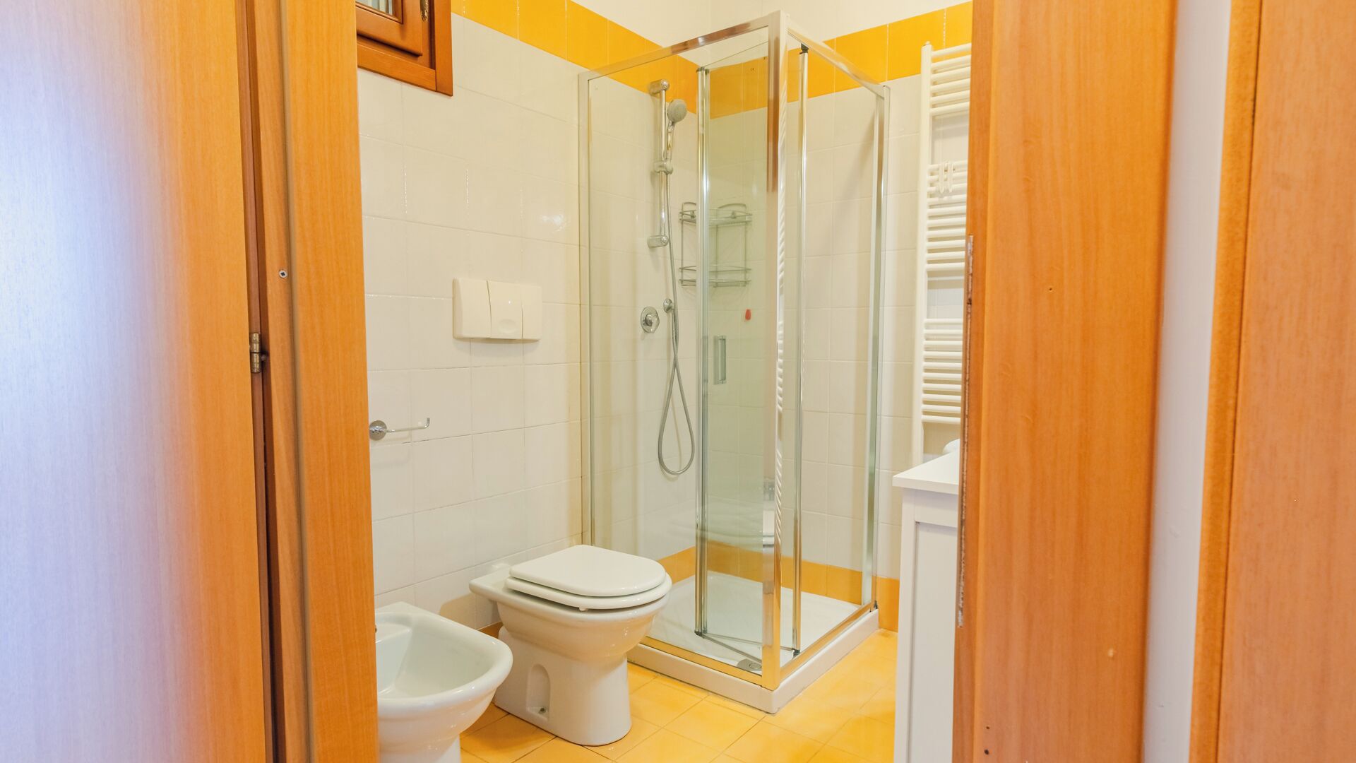 Een badkamer met een douchecabine van glas, een toilet en een bidet.
