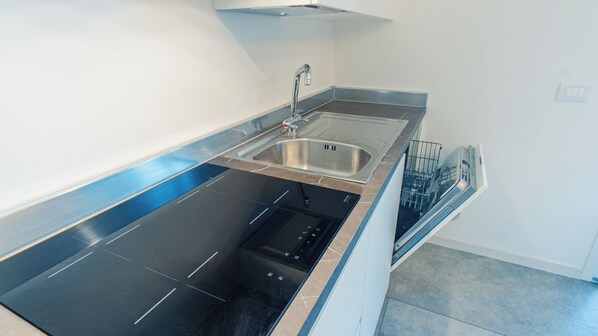 A modern kitchen with a stainless steel sink, a dishwasher, and a built-in oven.