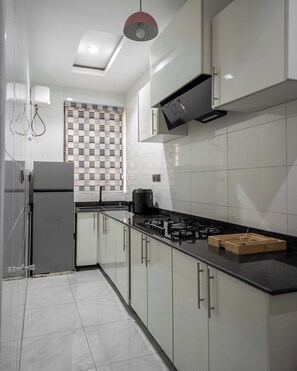 A modern kitchen with white cabinets, a black countertop, and a gas stove.